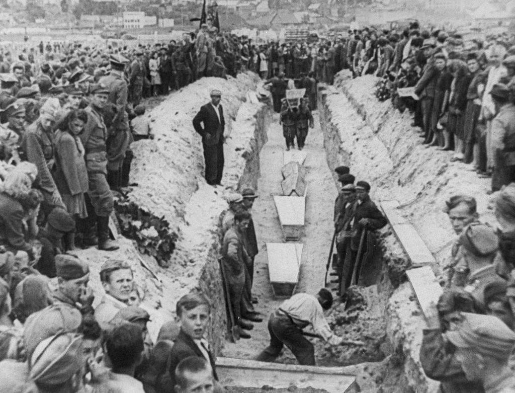 In this July 1946 file photo mourners crowd around long a narrow trench as coffins of victims of an anti-Semitic massacre are placed in a common grave following mass burial service, in Kielce, Poland. The July 4,1946, massacre killed 42 people, most of them Jews, and wounded over 80 