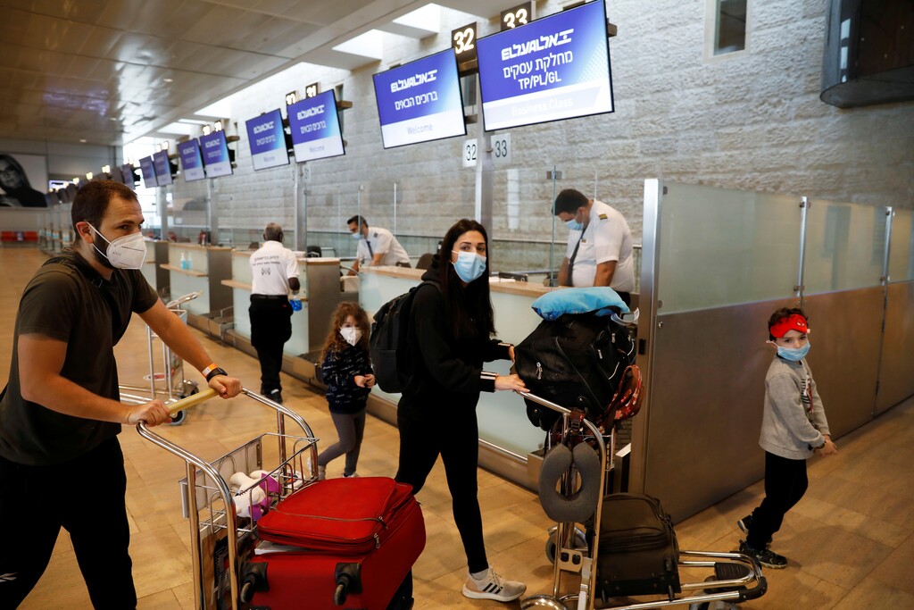 Passengers wearing masks push trolleys at the departures terminal at Ben Gurion Airport 