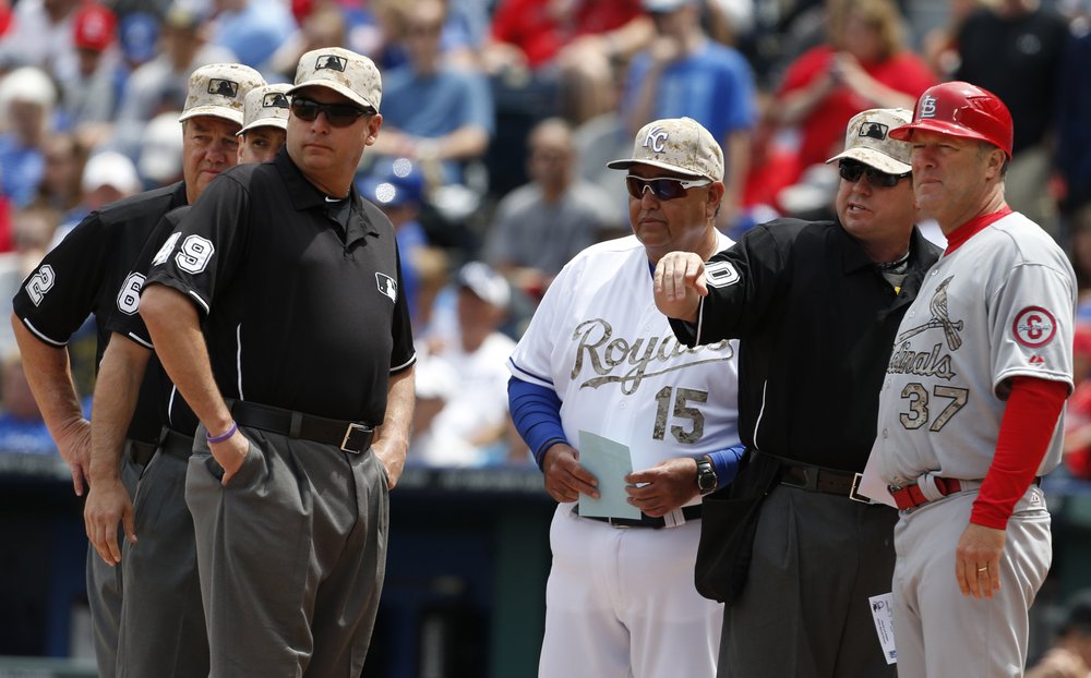 Kansas City Royals bench coach Chino Cadahia (15) and St. Louis Cardinals first base coach Chris Maloney (37) exchange line-ups with home plate umpire Rob Drake (30) before a baseball game at Kauffman Stadium in Kansas City 