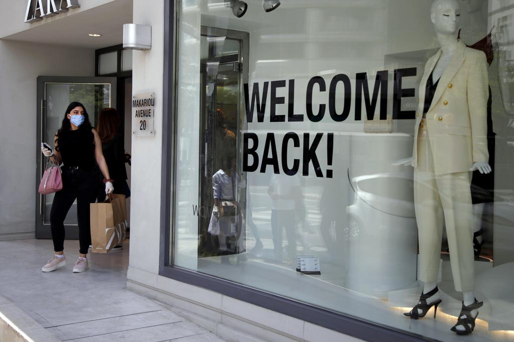 a woman wearing a face mask exits from a shop along Makarios Avenue, a busy shopping street in central Nicosia, Cyprus.