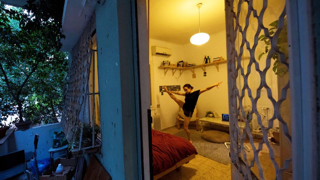 Yael Ben Ezer, a dancer from Israel's Batsheva Dance Company, is seen through a window while she practices in her apartment 