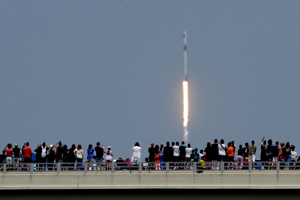 Spectators watch from a bridge in Titusville, Fla., as SpaceX Falcon 9 lifts off 