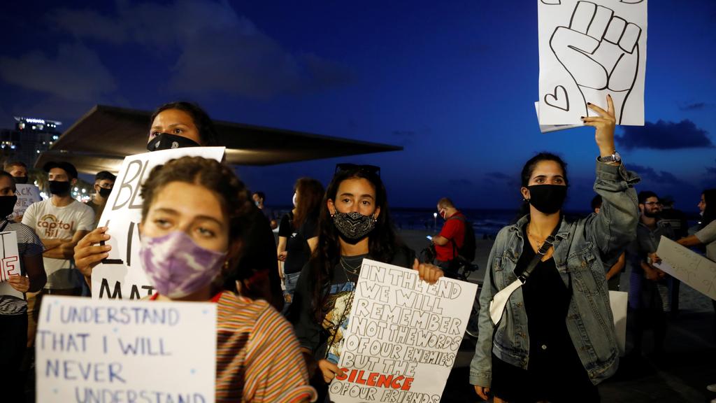 People hold placards as they protest in solidarity with those in the United States protesting police brutality and the death in Minneapolis police custody of George Floyd, in Tel Aviv 