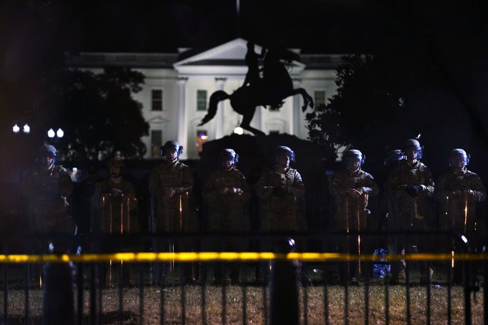 With the White House in the background, a line of police forms behind a fence in Lafayette Park as demonstrators gather to protest the death of George Floyd 