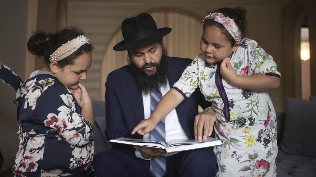 Rabbi Levi Banon and his daughters read a book inside their home in Casablanca, Morocco