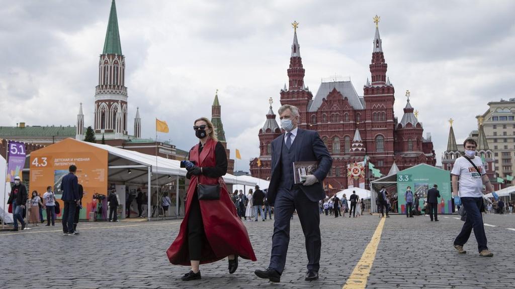 People wearing face masks to protect against coronavirus walk an outdoor book market set up in Red Square with a Historical museum in the background in Moscow, Russia 