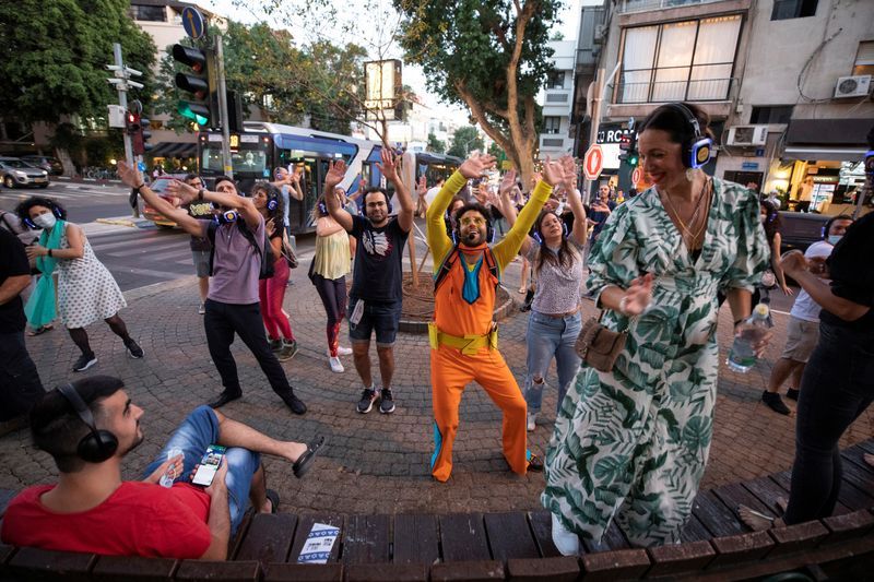 People taking part in a silent disco event wear headphones and dance on the pavement 