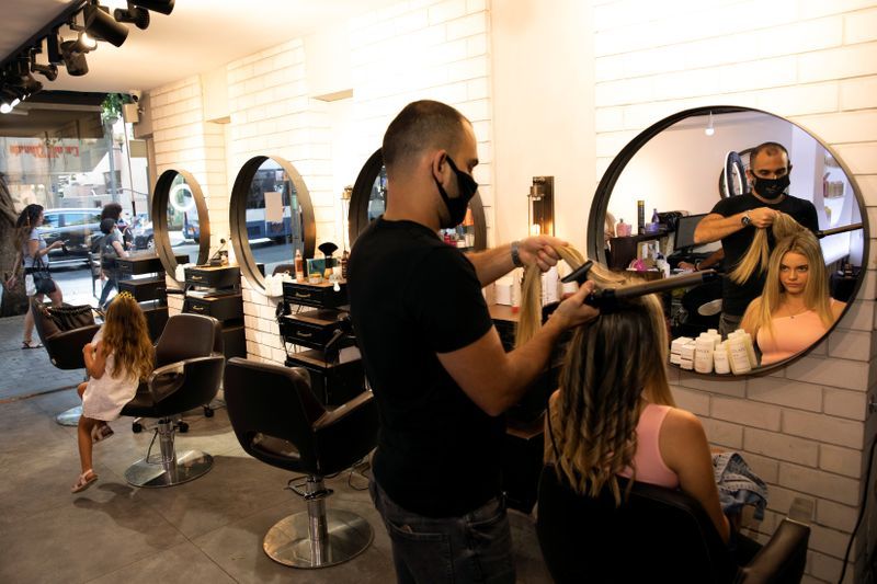 A hairdresser, wears a mask while working 