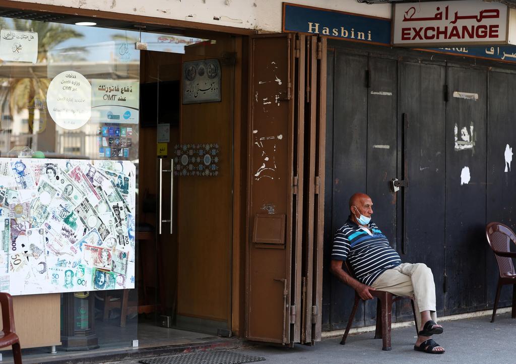 A man sits outside of a currency exchange shop in Beirut, Lebanon 