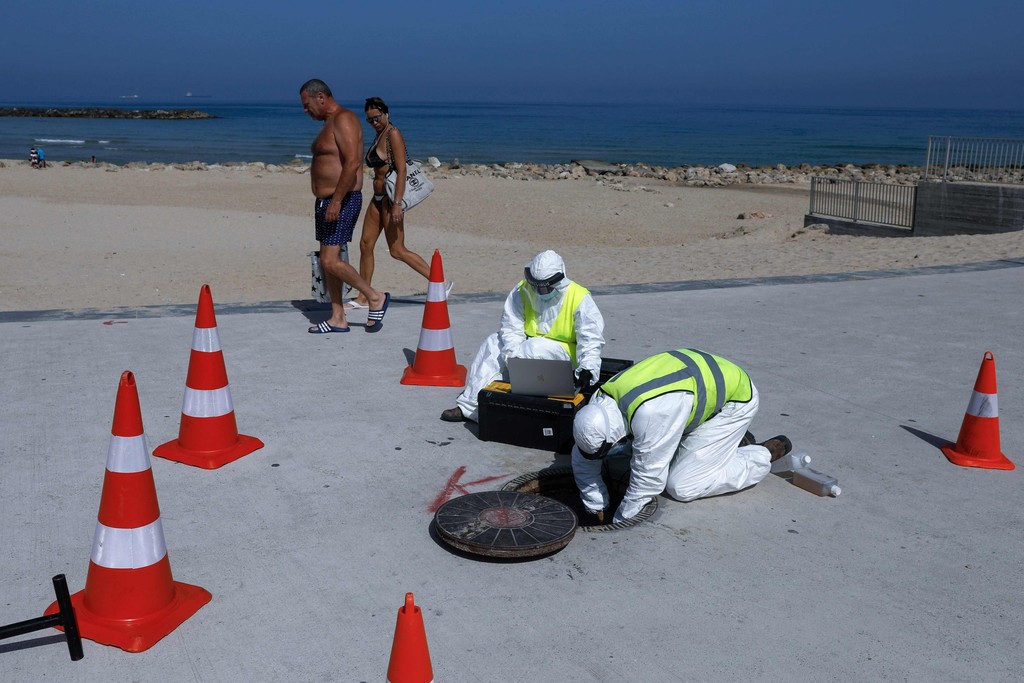 Technicians from Israeli firm Kando extract sewage samples from a manhole near the beach, in the southern coastal Israeli city of Ashkelon 