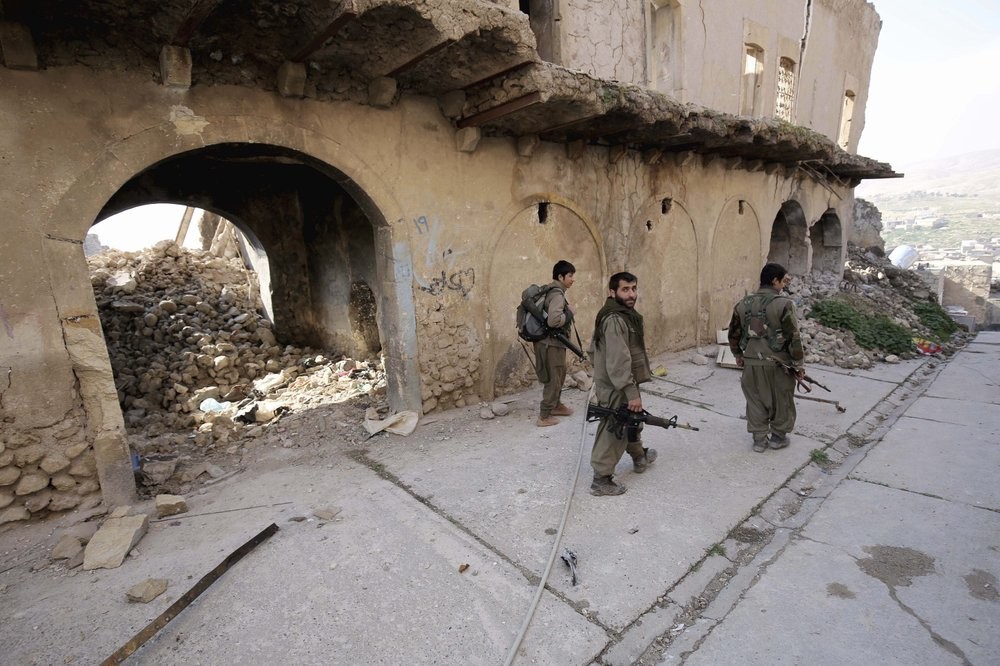 Fighters of the Turkey-based Kurdish Workers' Party (PKK) walk in the damaged streets of Sinjar, Iraq 