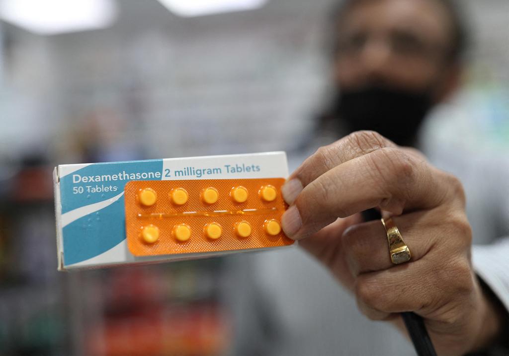 A member of staff at a pharmacy in London holds a packet of anti-inflammatory drug dexamethasone 