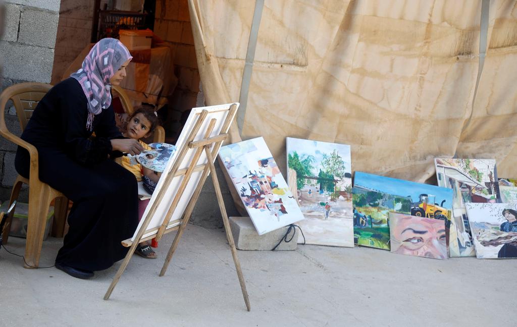 Bisharat painting conflict-inspired artwork as her daughter, Means, watches her