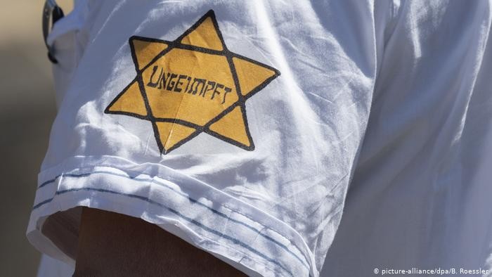 מפגין בגרמניה עם הטלאי הצהוב בו מופיעה המילה ״לא מחוסן״ במקום המילה  ״יהודי" 