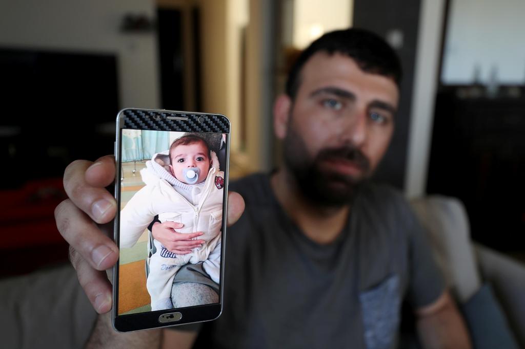 Ahmed Yaghi, the father of Palestinian infant Omar, who died of illness, shows his picture on his mobile phone in the central Gaza Strip 