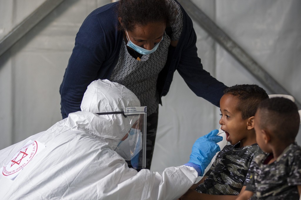 A child is tested for coronavirus by a healthcare worker at testing center for migrants in Tel Aviv 