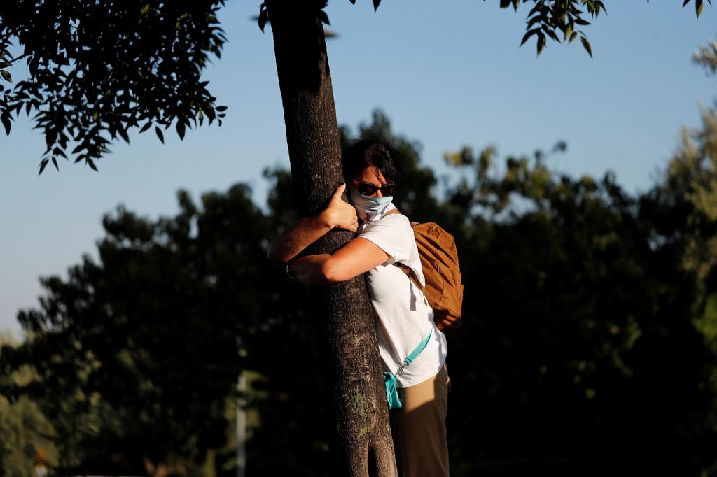 A woman takes part in a campaign by Israel's Nature and Parks Authority calling on people to join sightseeing tours and find comfort in tree hugging amid a spike in the coronavirus disease (COVID-19), in Jerusalem 