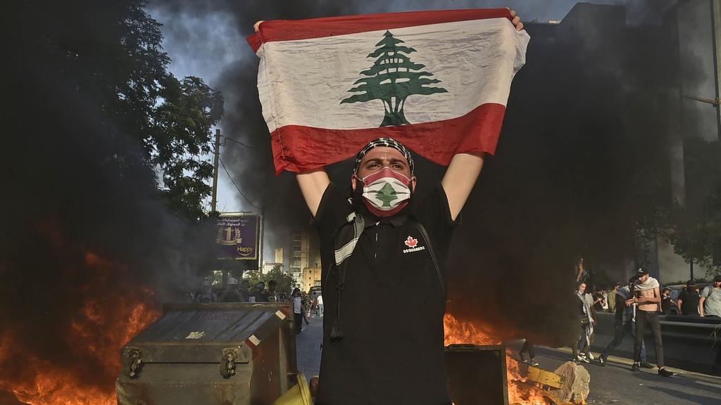 A protester holds up the Lebanese flag during a demonstration in Beirut, June 2020 