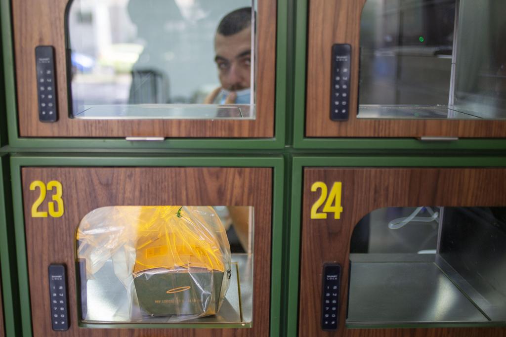 A customer reads the menu at Go noodles, where her order will be served in one of the glass-paned lockers seen behind her