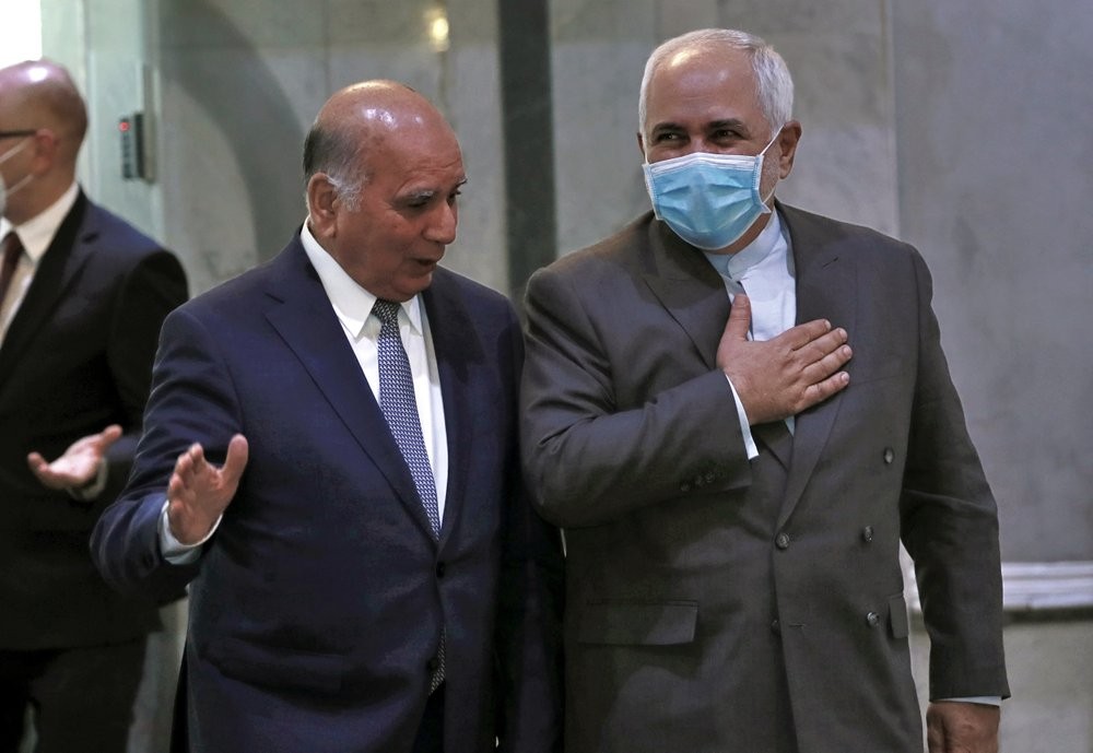 Iranian Foreign Minister, Mohammad Javad Zarif, right, wears a mask to help prevent the spread of the coronavirus walks with his Iraqi counterpart, Fouad Hussein during his visit to Baghdad, Iraq 