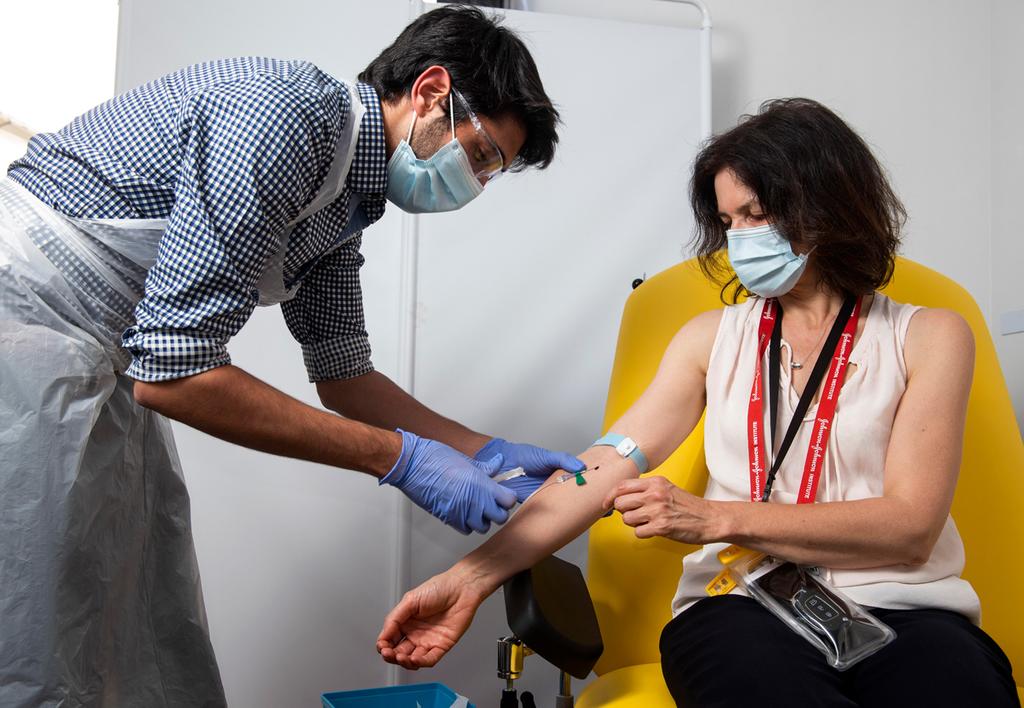 In this handout photo released by the University of Oxford, a doctor takes blood samples for use in a coronavirus vaccine trial in Oxford, England, on June 25, 2020 