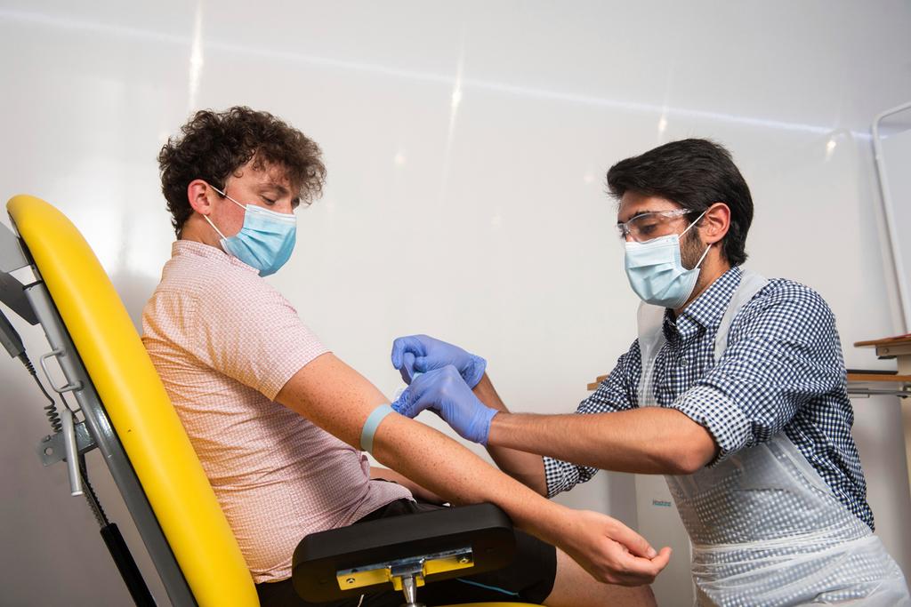 In this handout photo released by the University of Oxford, a doctor takes blood samples for use in a coronavirus vaccine trial in Oxford, England 