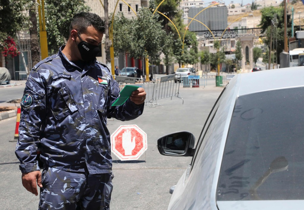 A member of the Palestinian security forces controls the cars entering the West Bank town of Hebron 