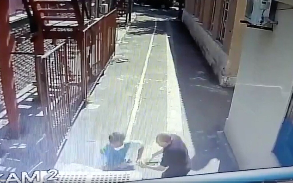 Screen capture from video of a security guard outside a synagogue in Ukraine struggling with an ax-wielding attacker 
