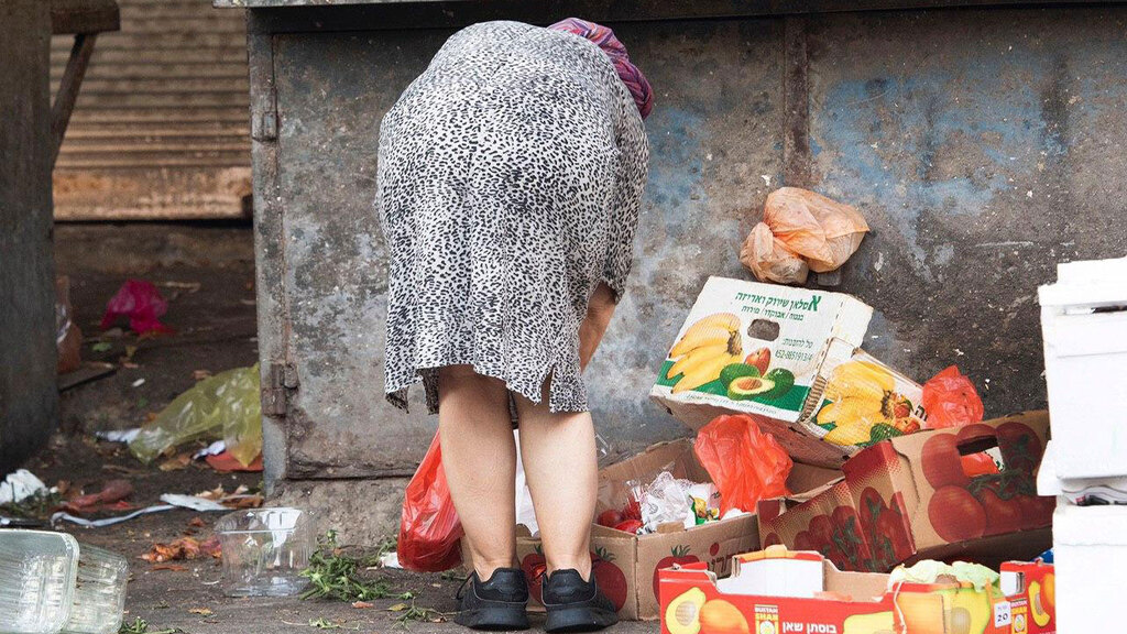 Женщина роется в мусоре в поисках продуктов (Фото: Надав Абас) אנשים מחפשים אוכל בפחים בצל משבר הקורונה