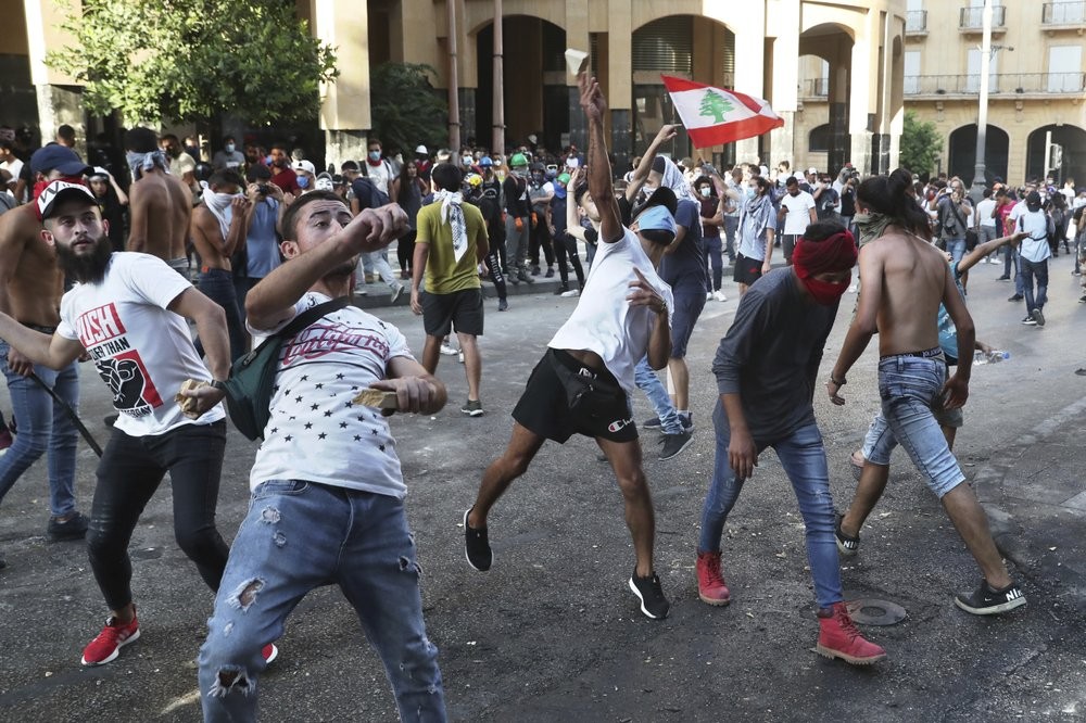 Protesters throw stones against the Lebanese riot police, during anti-government protest following Tuesday's massive explosion which devastated Beirut, Lebanon 