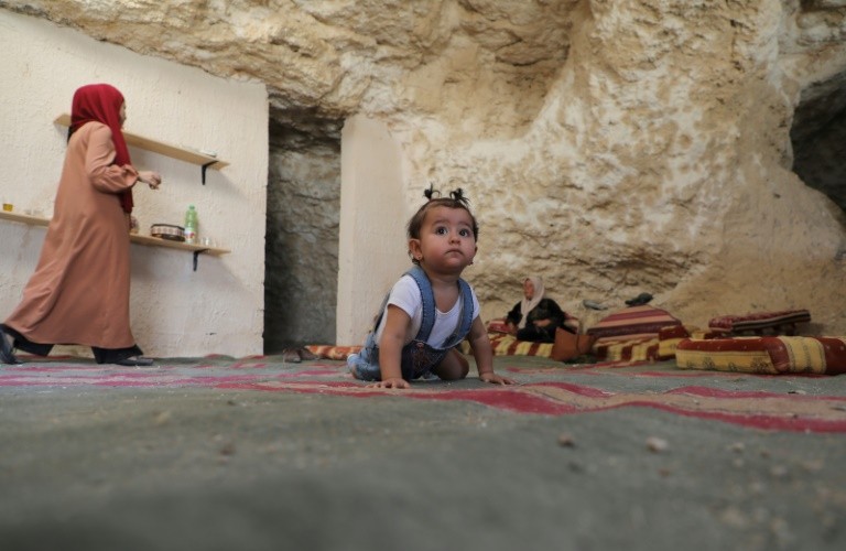 The daughter of Ahmed Amarneh crawls on a carpet at his home built in a cave, in the village of Farasin, west of Jenin, in the northern West Bank 