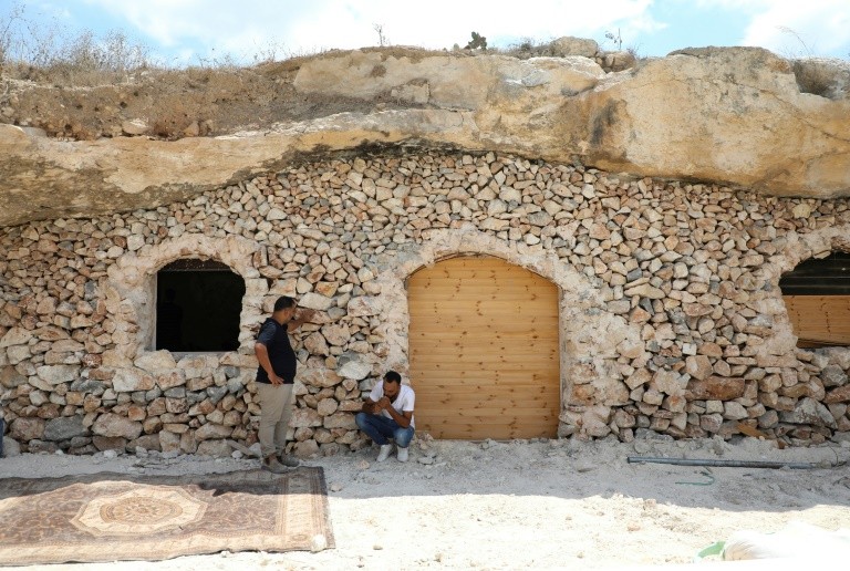 Ahmed Amarneh and a neighbor chat outside his home, built in a cave in the village of Farasin, west of Jenin, in the northern West Bank 