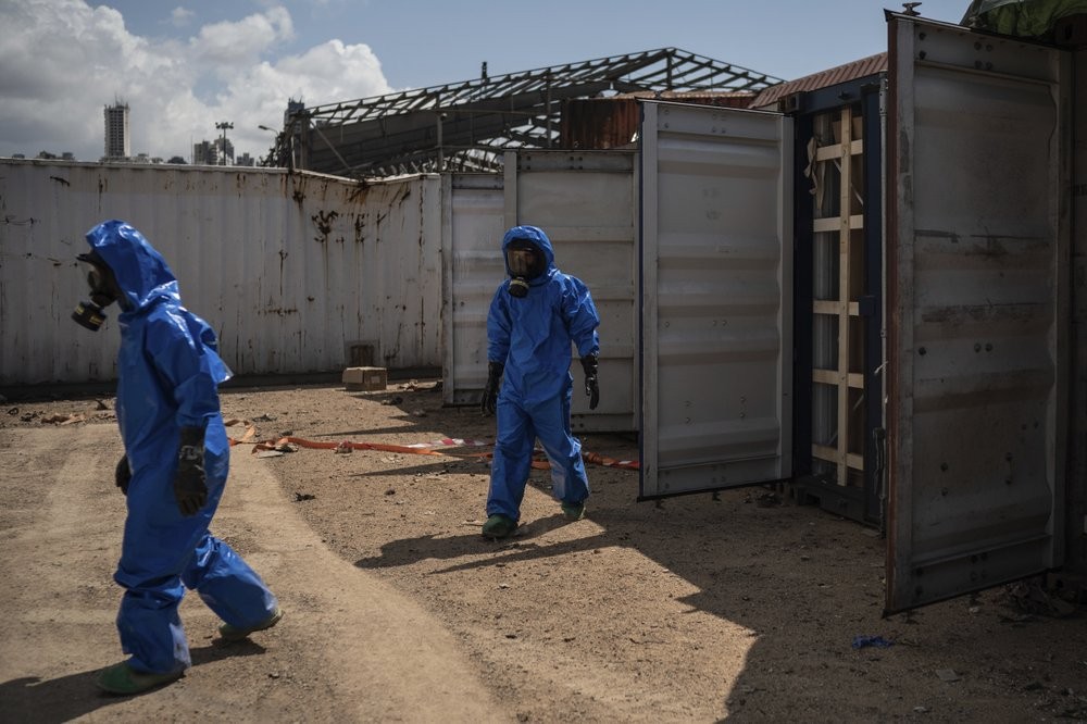 French emergency workers, part of a special unit working with chemicals, walk next to damaged containers near the site of last week's explosion, in the port of Beirut, Lebanon 