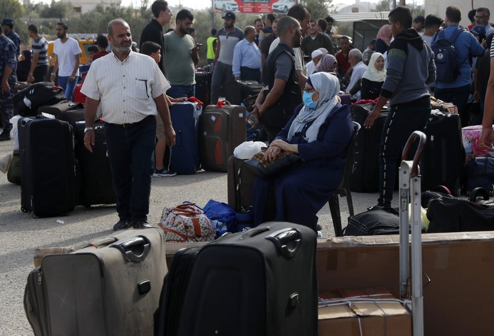 Passengers sit next to their luggage as they wait to cross the border to the Egyptian side of Rafah crossing, in Rafah, Gaza Strip 