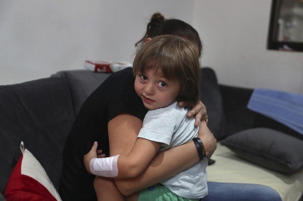 Hiba Achi hugs her son, 3-year-old Abed Itani, at her house in Beirut, Lebanon, Tuesday, Aug. 11, 2020. Abed was playing with his Lego blocks when the huge blast ripped through Beirut, shattering the nearby glass doors. He had cuts on his tiny arms and feet, a head injury, and was taken to the emergency room, where he sat amid other bleeding people