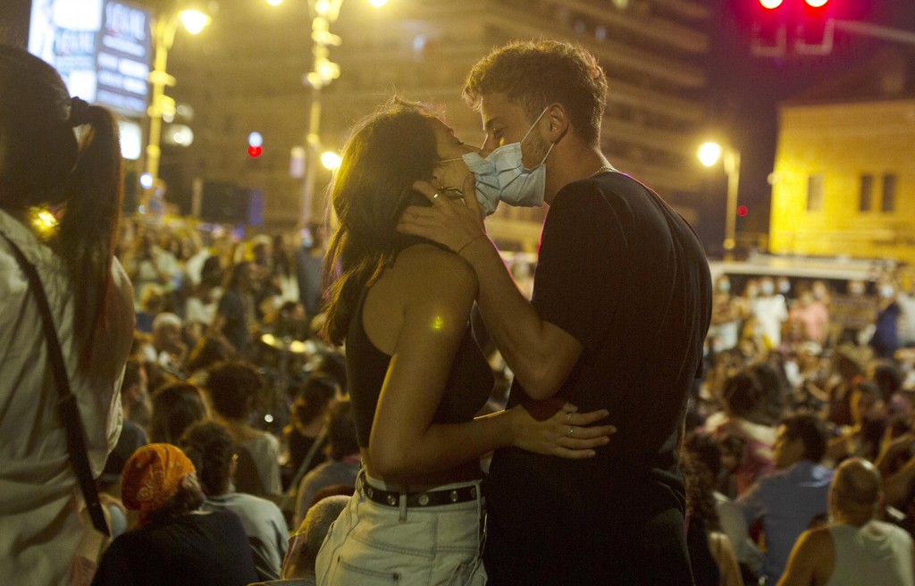 A couple kisses while wearing face masks to curb the spread of the coronavirus during a protest against Israel's Prime Minister Benjamin Netanyahu outside his residence in Jerusalem 