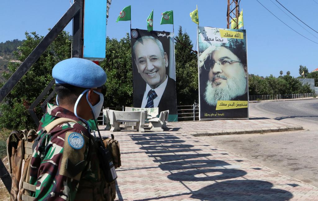 A United Nations peacekeeper (UNIFIL) stands near a poster depicting Lebanon's Hezbollah leader Hassan Nasrallah