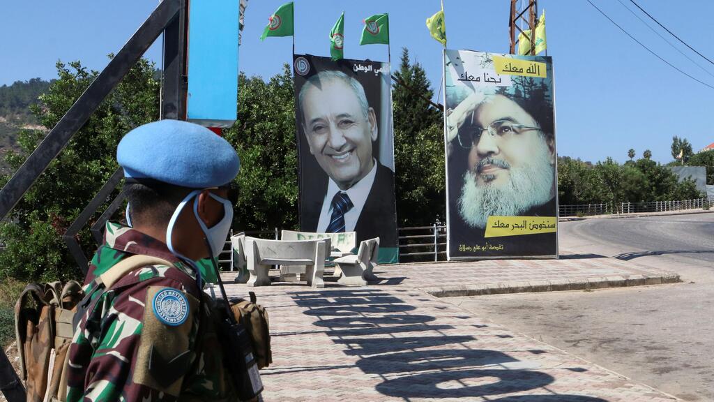 A United Nations peacekeeper (UNIFIL) stands near a poster depicting Lebanon's Hezbollah leader Hassan Nasrallah