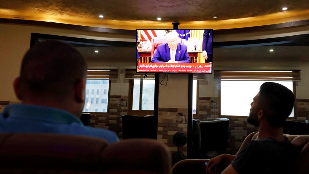 Palestinians in the West Bank city of Hebron watch as U.S. President Donald Trump announces the UAE-Israel agreement to normalize relations 