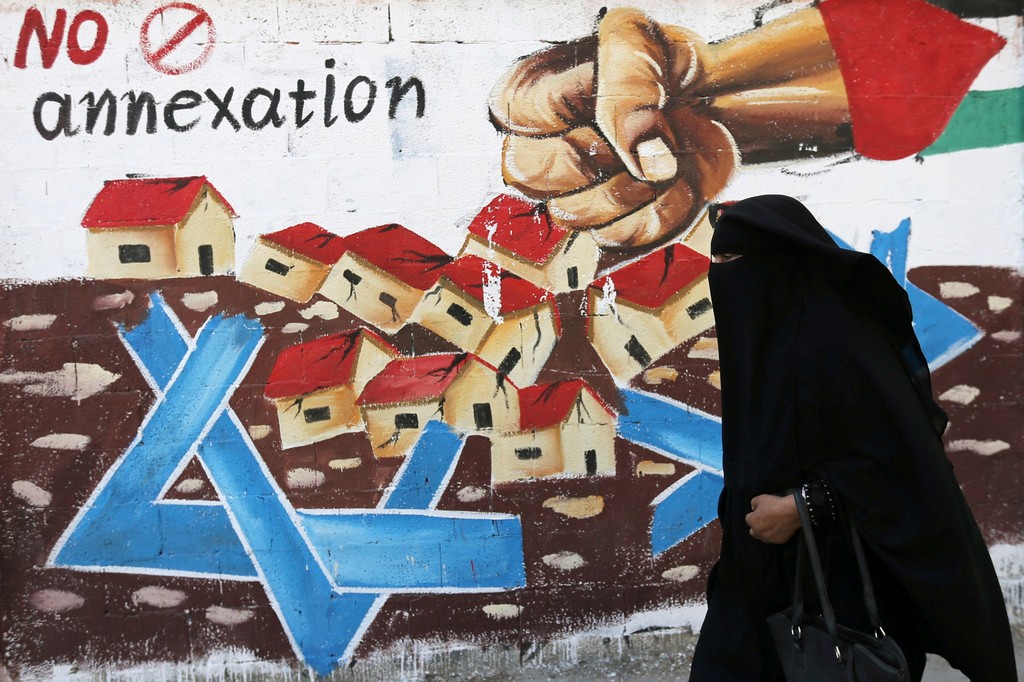 A Palestinian woman walks past a mural against Israel's plan to extend its sovereignty over parts of the West Bank, in Rafah in the southern Gaza Strip July 14, 2020
