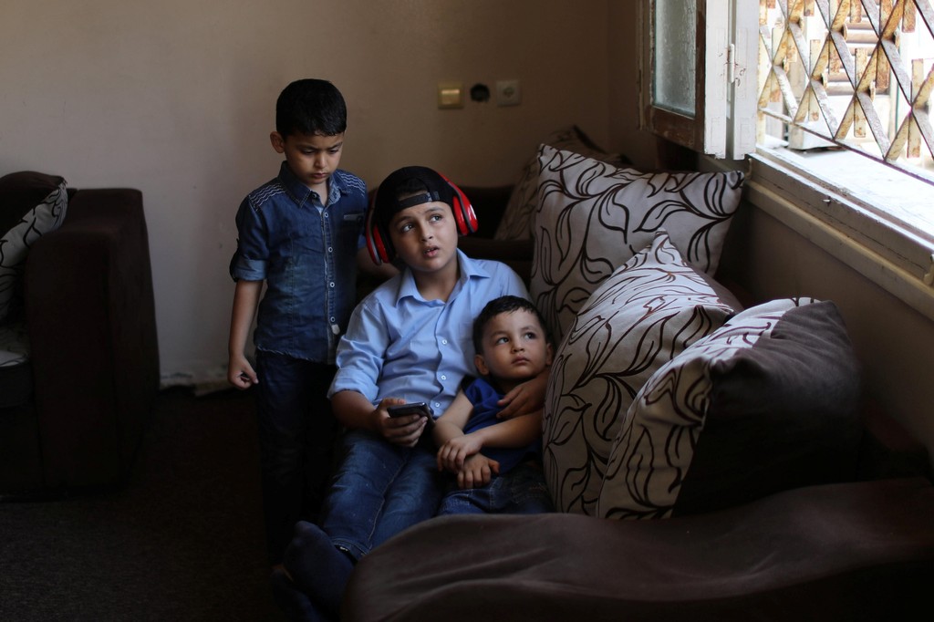 Abdel-Rahman Al-Shantti, an 11-year-old Gaza rapper, lies on a sofa with his brothers after returning home from school in Gaza City 