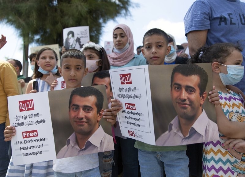 Aws, 7, left, and Amr, 9, hold posters with a picture of their father, Mahmoud Nawajaa, a leading coordinator of the Palestinian-led boycott movement against Israel, BDS, during a protest calling for the EU to press for his release, in front of the German Representative Office, in the West Bank city of Ramallah 