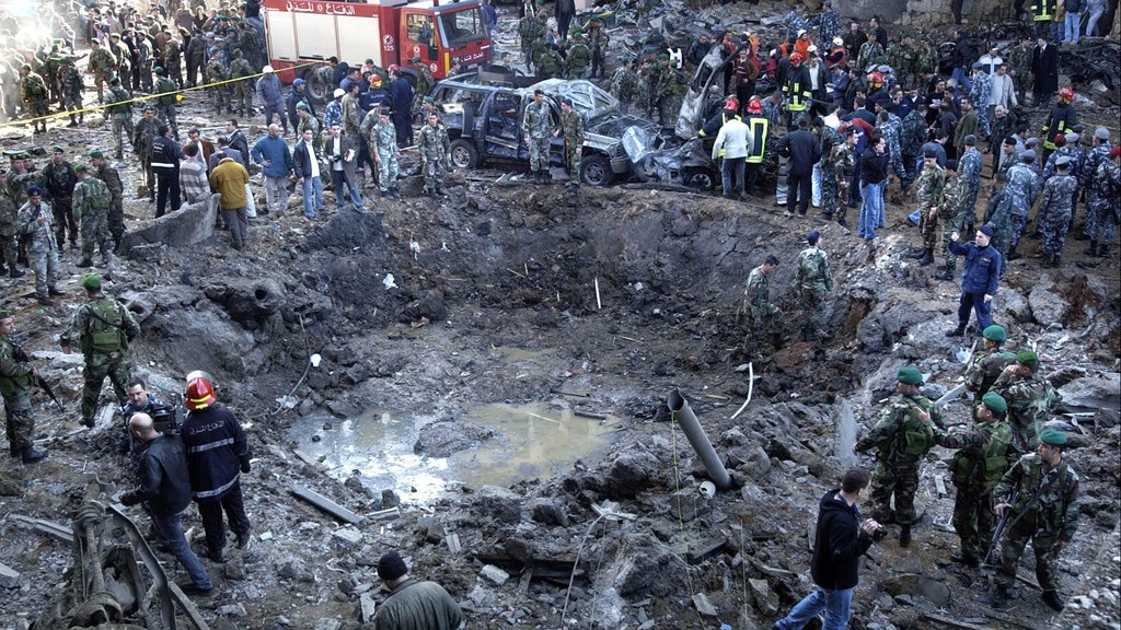  Rescue workers and soldiers stand around a massive crater after a bomb attack that tore through the motorcade of former Prime Minister Rafik Hariri
