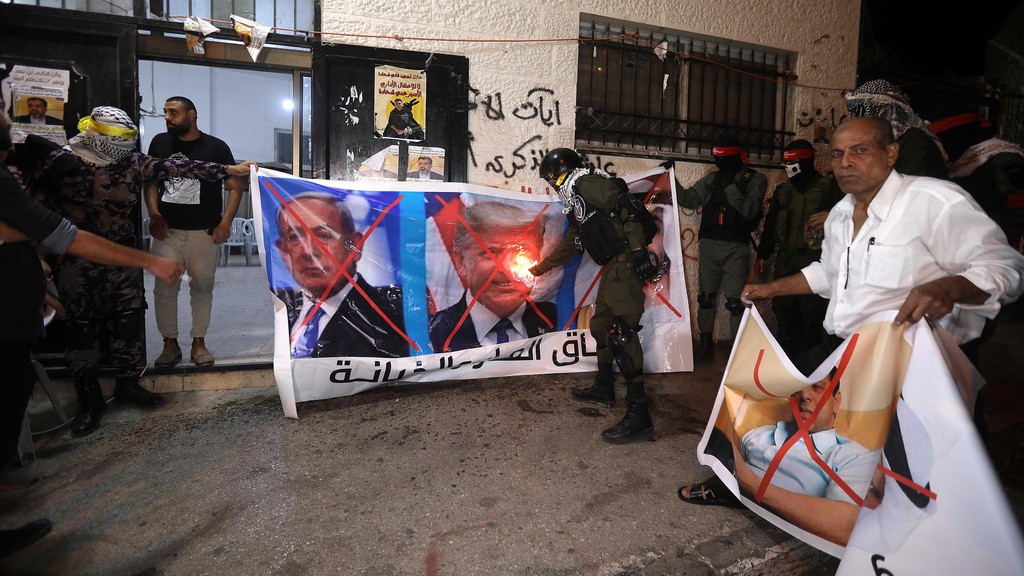 Palestinians burn banners depicting Abu Dhabi Crown Prince Mohammed bin Zayed al-Nahyan (R), Israeli Prime Minister Benjamin Netanyahu (L) and US President Donald J. Trump (C), during a protest against the peace agreement