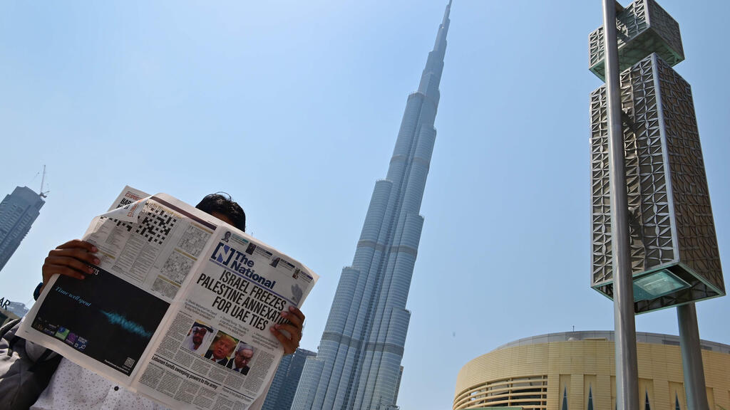 A man reads a copy of UAE-based The National newspaper near the Burj Khalifa