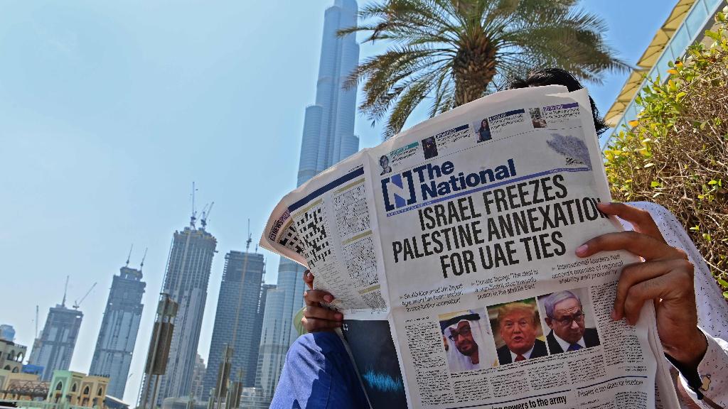  man reading a copy of  the UAE-based The National newspaper regarding the UAE-Israel agreement 