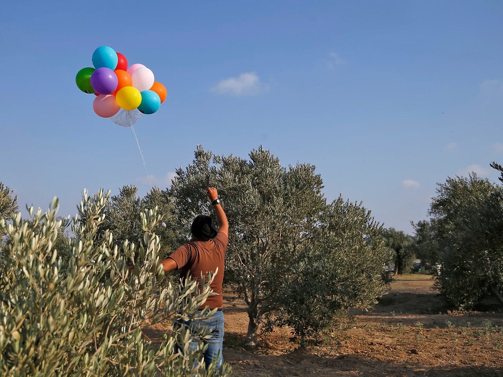 A Gazan man luanches a cluster of balloons carrying an incendiary device towards Israeli communities 