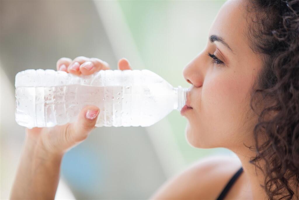אישה שותה מים קרים במהלך אימון