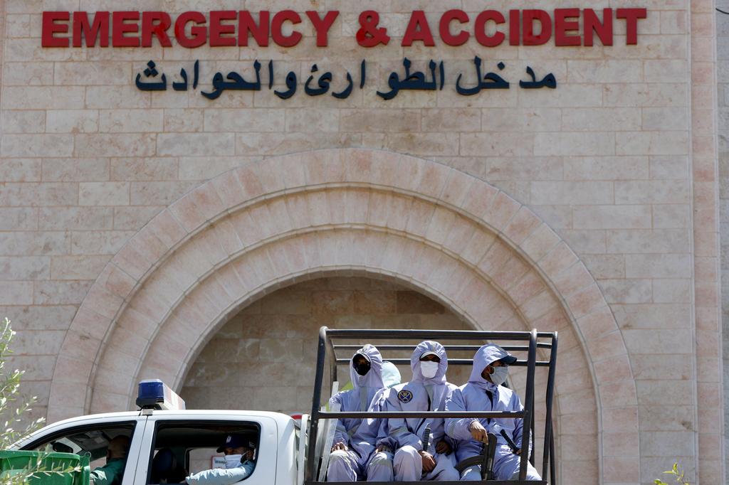 Members of Palestinian security forces wearing protective clothings ride on a truck in a hospital where a 61-year-old man died after contracting the coronavirus disease