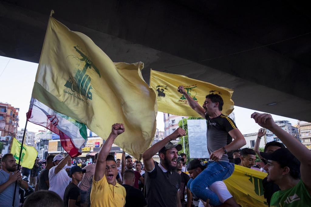 Hezbollah and Amal supporters wave Hezbollah and Iranian flags as they shout slogans against Israel and U.S. during a June 2020 protest in Beirut 